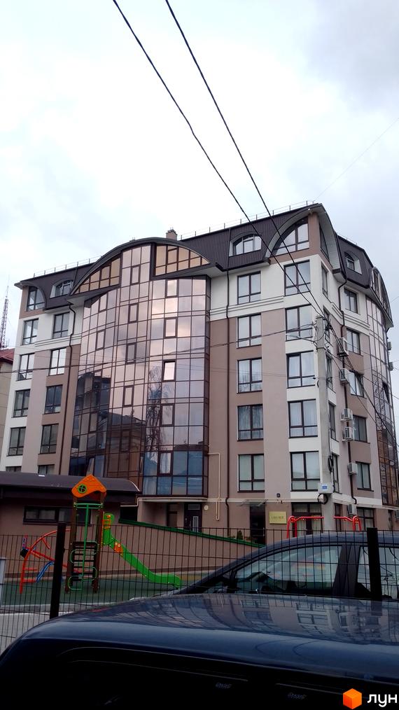 Житловий комплекс Charlie на бул. Шевченка, 31б, має вигнутий дах та великий скляний фасад. Перед будинком розташований дитячий майданчик.