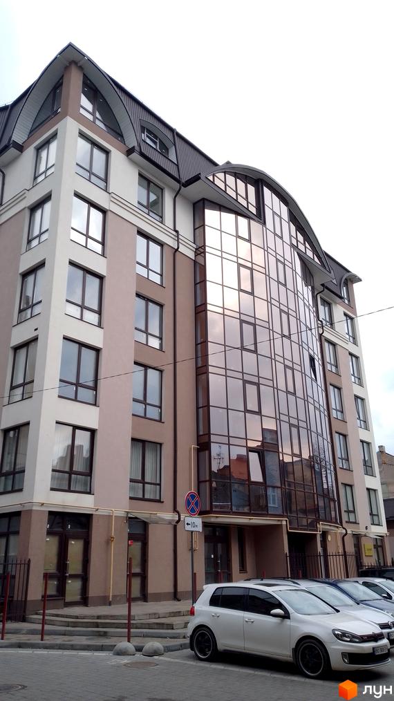 Багатоповерхова новобудова з панорамним склінням на бульварі Шевченка, 31б. На передньому плані припарковані автомобілі, поруч тротуар.