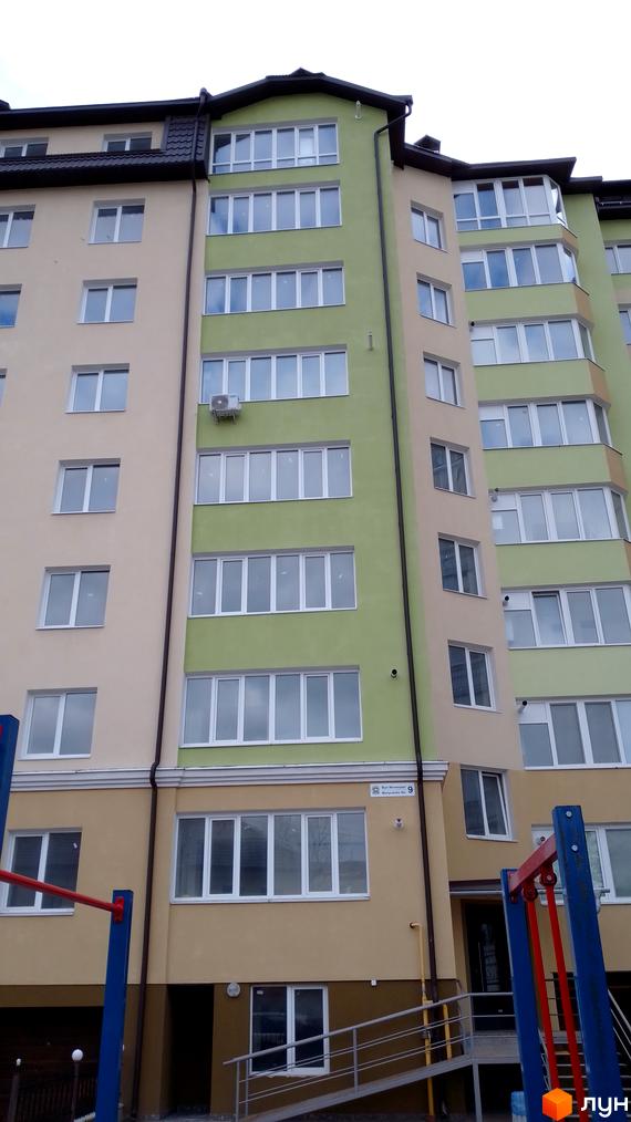 Фасад багатоповерхового будинку на вулиці Вояків Дивізії Галичина. Біля будинку дитячий майданчик з гірками та гойдалками.