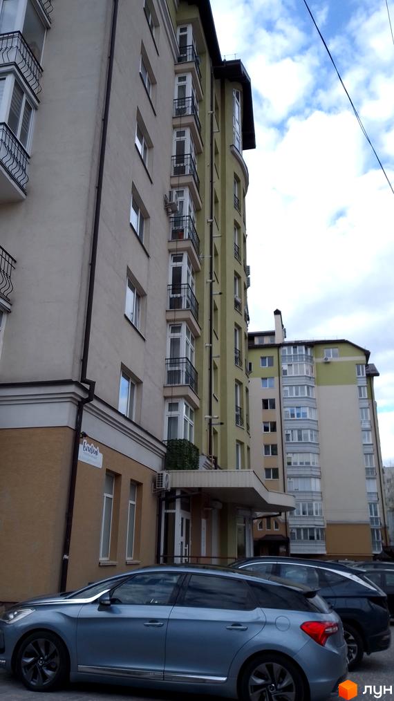 Зовнішній вигляд багатоквартирного будинку на вулиці Вояків Дивізії Галичина. Фасад будівлі з вікнами та балконами, припарковані автомобілі.