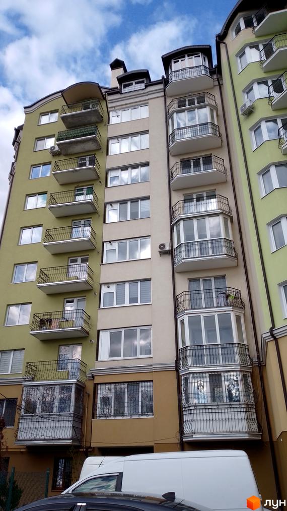 Зовнішній вигляд будинку на вулиці Вояків Дивізії Галичина. Багатоповерхова будівля з балконами та великими вікнами.