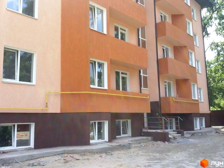 Житловий комплекс на вул. Українська, 85в, з фасадом у світлих тонах та прибудинковою територією, що потребує облаштування.