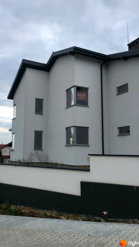 Світлий багатоквартирний будинок на вул. Собранецька, 60 з темним дахом та вікнами. Перед ним біла огорожа та бруківка.