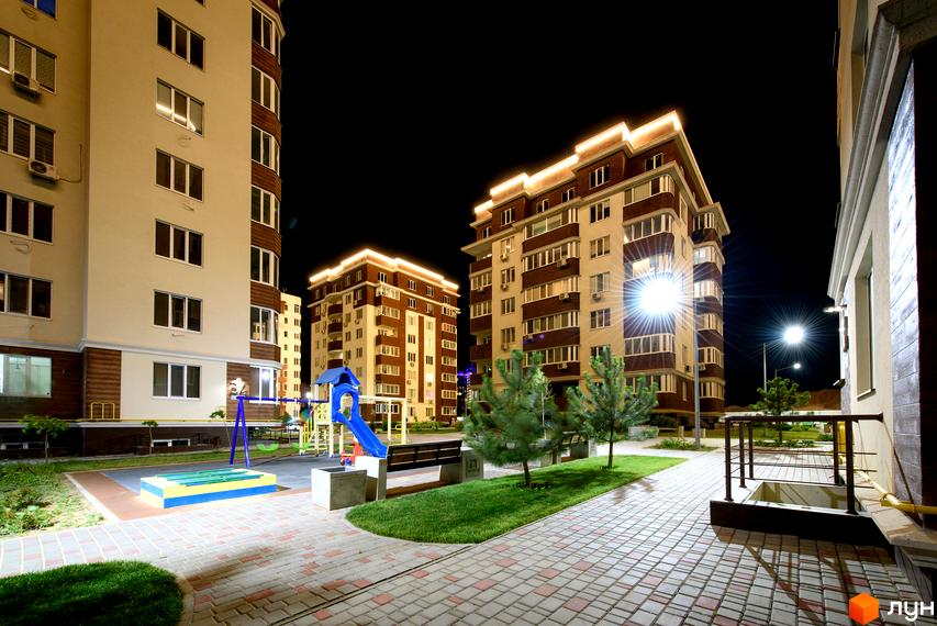 Житловий комплекс Золота Ера з підсвічуванням у вечірній час. На території є дитячий майданчик та лавки для відпочинку.