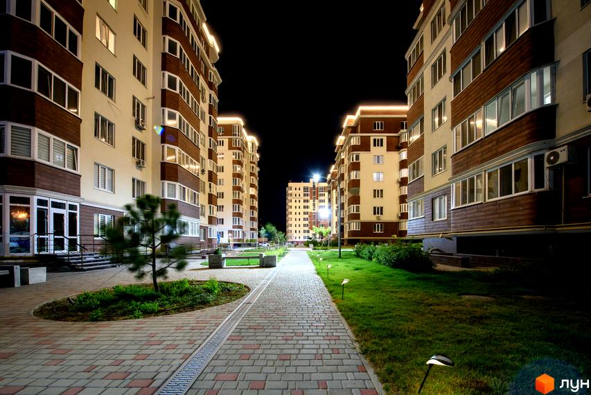 Житловий комплекс Золота Ера. Високі будинки з великими вікнами та декоративними панелями. Доглянута прибудинкова територія з доріжками та газонами.