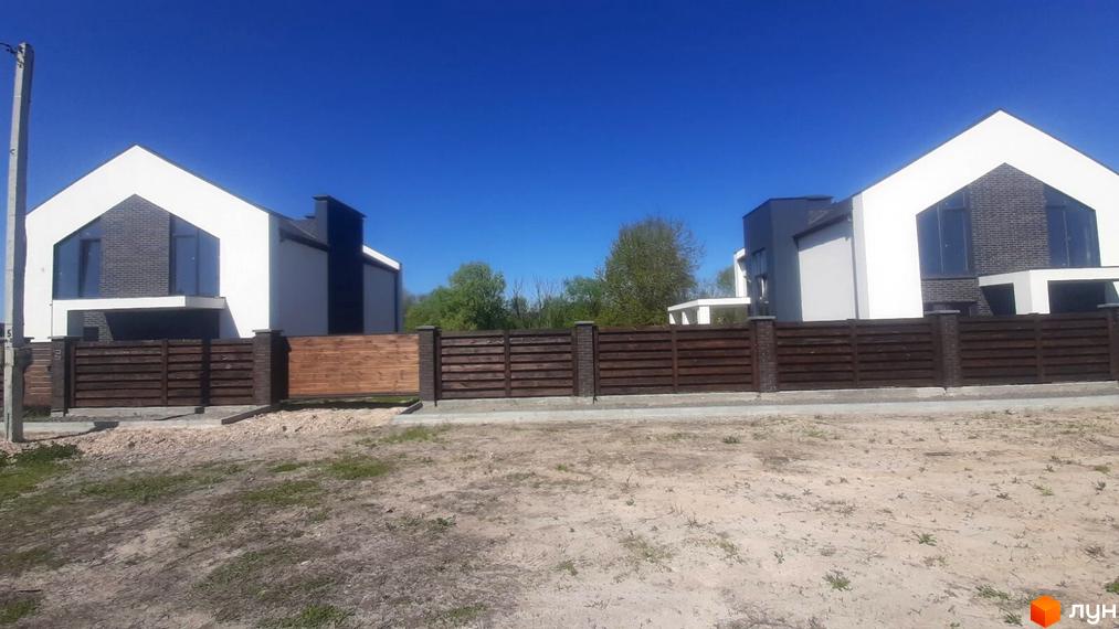 Два котеджі з білими фасадами, темними дахами та великими вікнами у Котеджному містечку біля Озер, відокремлені дерев'яним парканом.