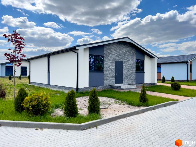 Котеджне містечко Millennium House: одноповерховий будинок з білими стінами, сірим фасадом та темним дахом. Навколо газон, дерева та бруківка.
