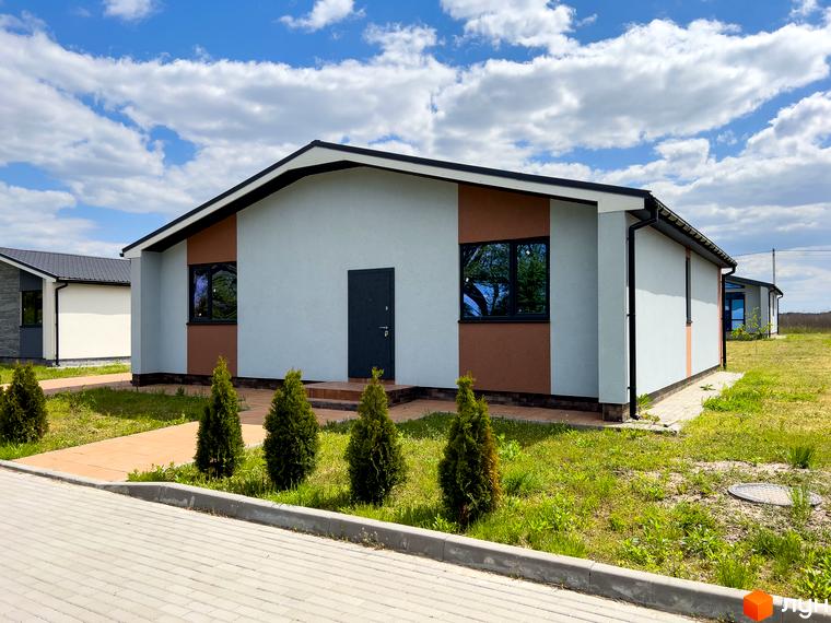 Зовнішній вигляд будинку в Котеджному містечку Millennium House з сірими стінами та коричневими вставками, перед будинком доглянута прибудинкова територія з газоном та тротуарною плиткою.