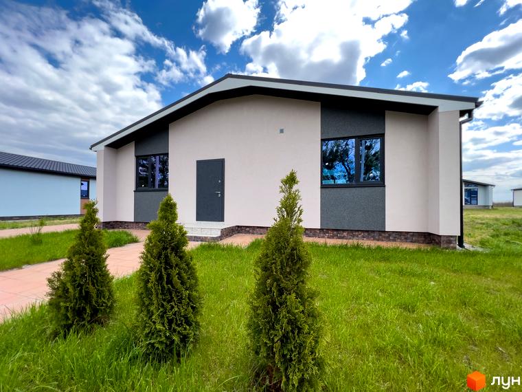 Зовнішній вигляд будинку в Котеджному містечку Millennium House з білими стінами, темним дахом та вікнами. На передньому плані зелена трава та туї.