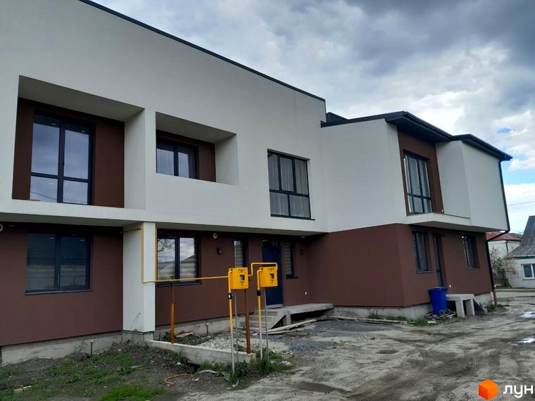 Двоповерховий житловий комплекс за адресою вул. Шевченка, 116б, з білим та коричневим фасадом. Прибудинкова територія має ґрунтове покриття та газові комунікації.