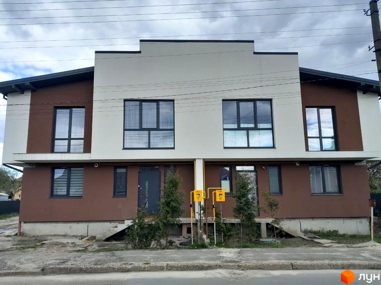 Новобудова на вул. Шевченка, 116б: двоповерховий будинок з коричневим та білим фасадом, темними вікнами. На території є газові лічильники та дерева.