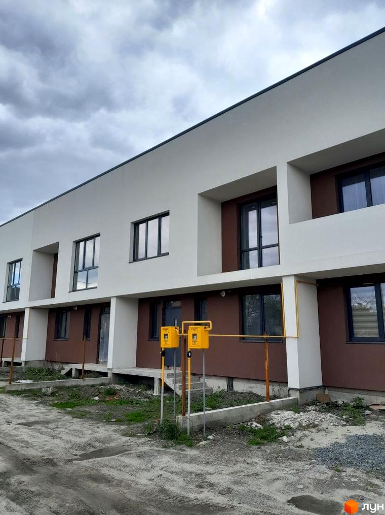 Фасад Житлового комплексу на вул. Шевченка, 116б: білі та коричневі секції, темні вікна. Прибудинкова територія ґрунтована.