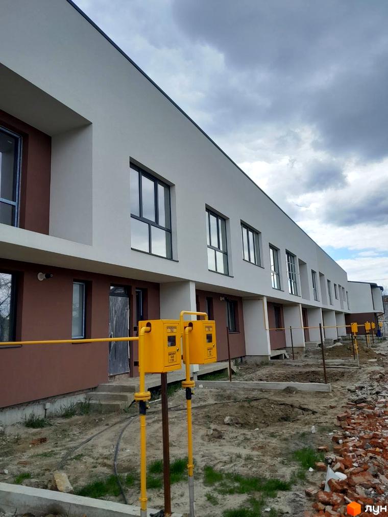 Фото нового житлового комплексу на вул. Шевченка, 116б: двоповерхові будинки з білим та коричневим фасадом, поруч будівельний майданчик.