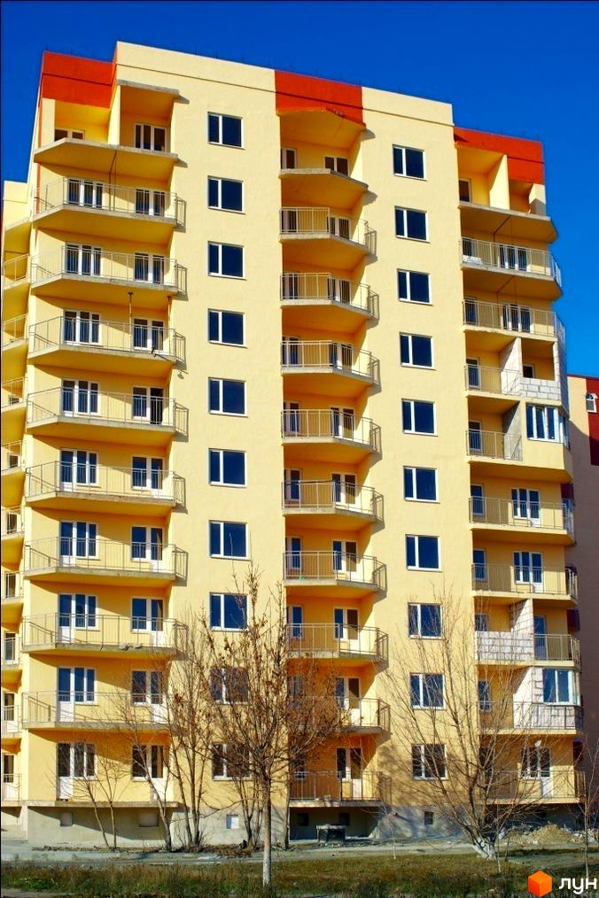 Житловий комплекс Таврійський з жовтою фасадною обробкою та балконами. Прибудинкова територія з деревами та зеленими насадженнями.