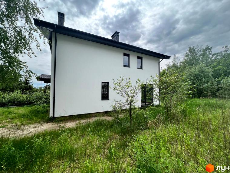 Зовнішній вигляд будинку в Котеджному містечку GREEN CLUB. Навколо будинку зелена трава та дерева.