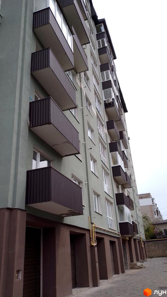 Новобудова на вул. Глибока, 24 з фасадом світло-зеленого кольору, темно-коричневими балконами та вимощеною прибудинковою територією.