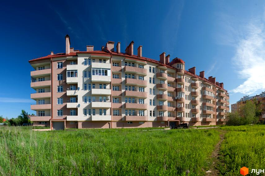 Житловий комплекс Нова Рафанда з фасадом та балконами, оточений зеленою прибудинковою територією.