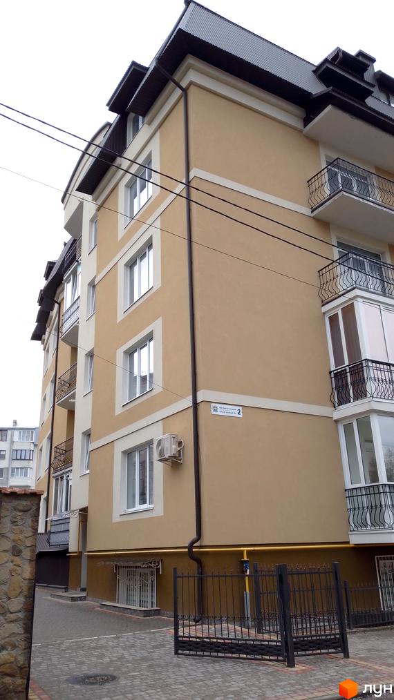Багатоквартирний будинок за адресою вул. Братів Гжицьких, 2, з бежевим фасадом та балконами. Прибудинкова територія вимощена бруківкою.