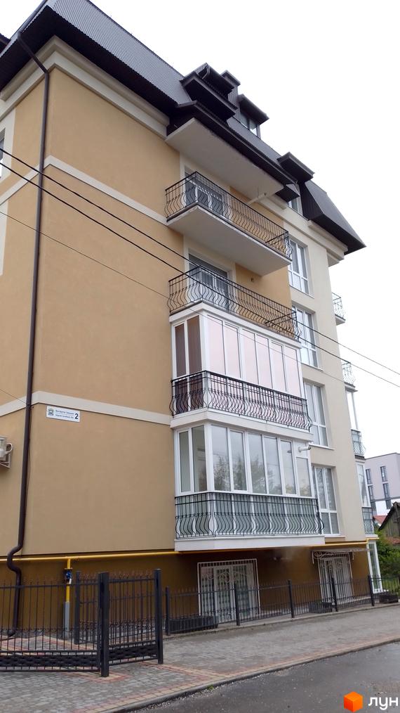 Зовнішній вигляд будинку Житловий комплекс по вул. Братів Гжицьких, 2 з кованими балконами та огорожею, бруківкою та газоном.