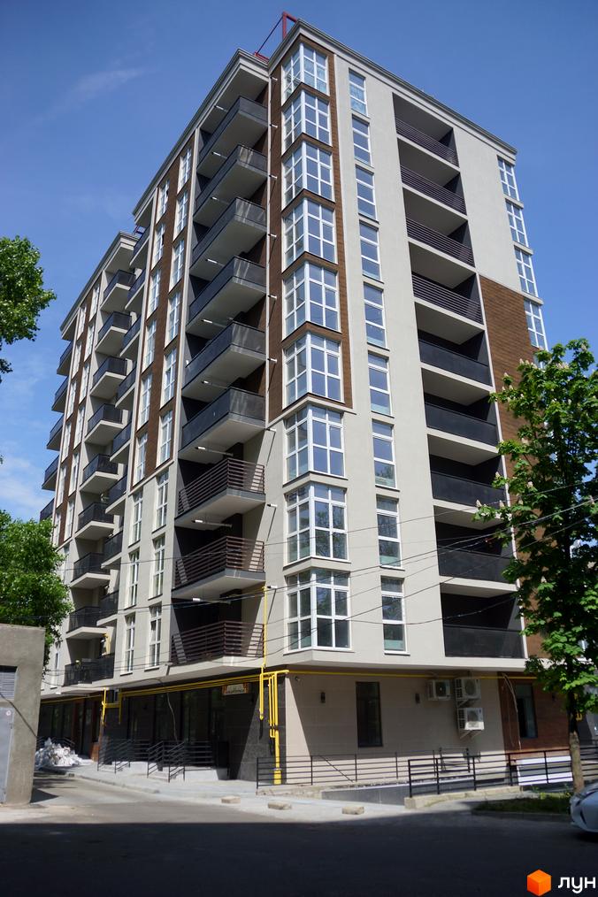 Зовнішній вигляд житлового комплексу Лотос Холл з численними балконами та великими вікнами. Навколо будівлі розташована прибудинкова територія з зеленими насадженнями.