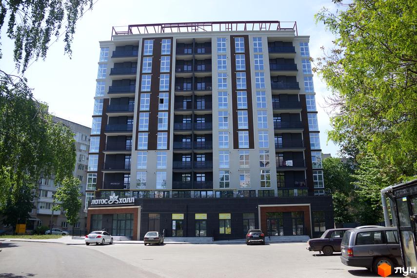 Зовнішній вигляд житлового комплексу Лотос Холл з численними вікнами та балконами, розташованого біля дороги з припаркованими автомобілями та деревами.