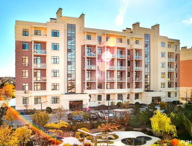 Житловий комплекс Парк Совіньйон: багатоповерхова будівля з цегляними та світлими фасадами, балконами та скляним ліфтовим холом. На прибудинковій території розташовані дерева, ландшафтний дизайн та місця для відпочинку.