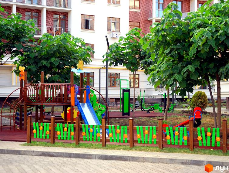 Житловий комплекс Парк Совіньйон: вид на сучасну новобудову з дитячим майданчиком та зонами для відпочинку. Зелена територія комплексу з деревами та елементами благоустрою.