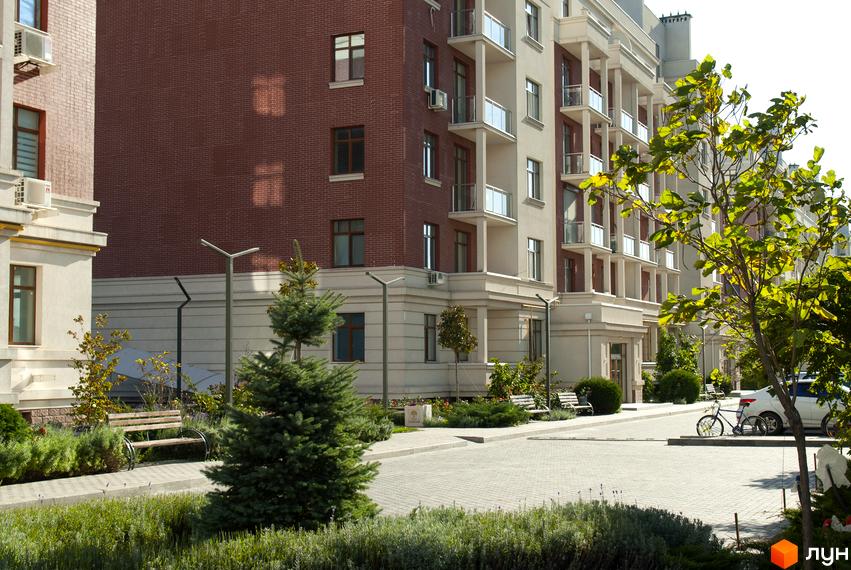 Житловий комплекс Парк Совіньйон. Фасади будівель з цегляними та світлими елементами, балконами. Прибудинкова територія з деревами, лавками та доріжками.