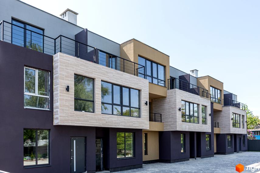 Зовнішній вигляд таунхаусів Rusaniv Gardens з терасами та панорамними вікнами. Бруківка перед будинками.