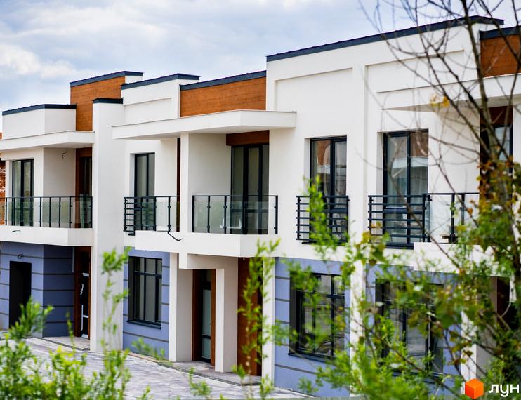 Котеджне містечко КМ City Villa Club: фасади будинків з великими вікнами та балконами, дерева навколо.