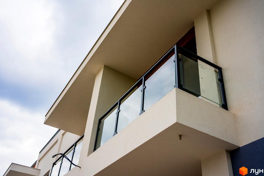 Зовнішній вигляд будинку КМ City Villa Club з балконами та скляними перилами. Сучасний житловий комплекс з елегантним дизайном.