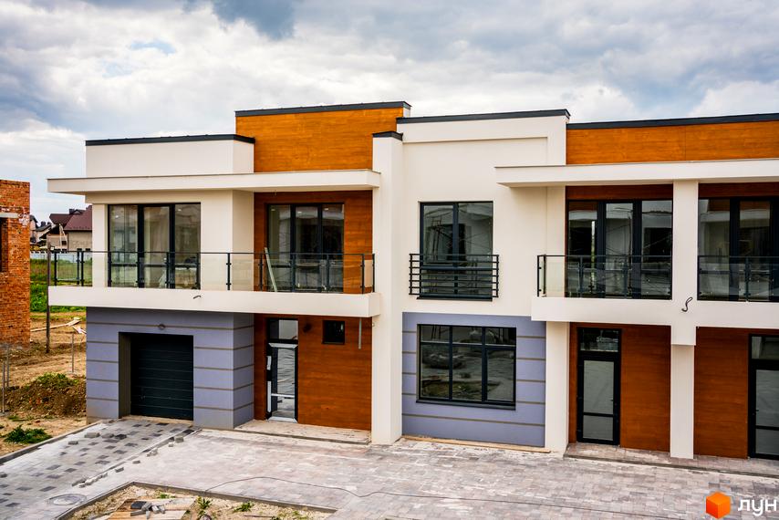 Котеджне містечко КМ City Villa Club. Фасад будинку з дерев'яними елементами, великими вікнами та балконами. Поруч облаштована прибудинкова територія з бруківкою.