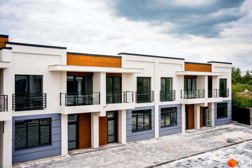 Котеджне містечко КМ City Villa Club: фасади будинків з дерев'яними елементами, великими вікнами та балконами. Прибудинкова територія з бруківкою.