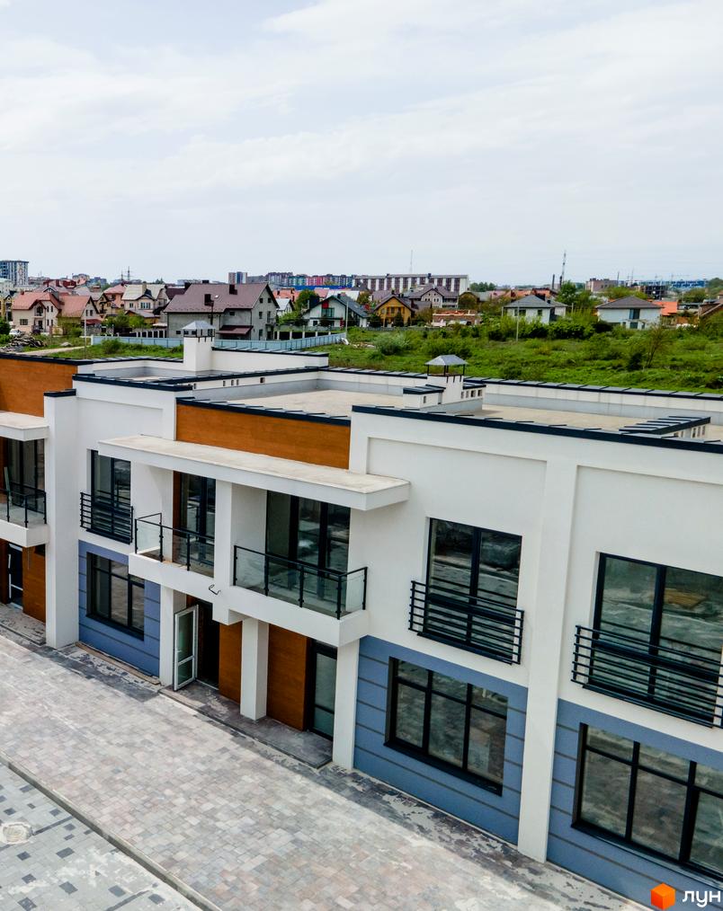 Котеджне містечко КМ City Villa Club: фасади будинків з великими вікнами та балконами, вимощені бруківкою доріжки.