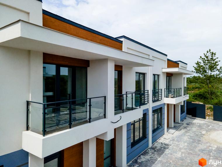 Котеджне містечко КМ City Villa Club. Фасад будинку з балконами та панорамними вікнами, прибудинкова територія з бруківкою.