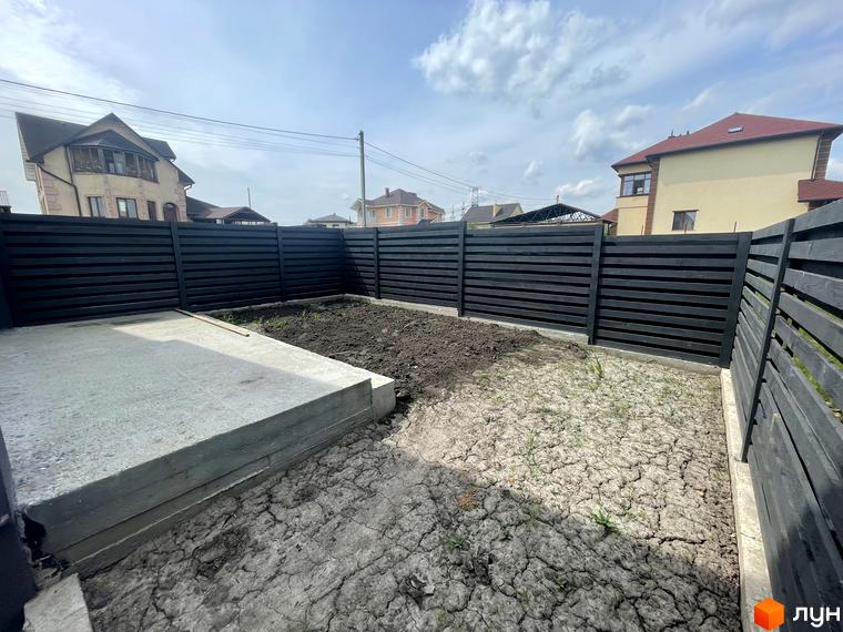 Будівельний проєкт Дуплекси „На Зоряному“ з чорним парканом та бетонною плитою на прибудинковій території.