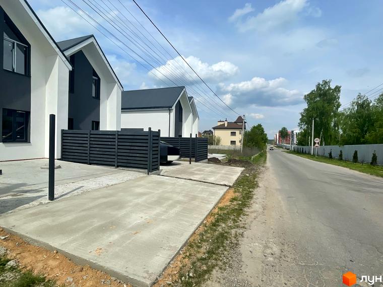 Дуплекси „На Зоряному“ – це новобудова з біло-сірими фасадами та темними дахами, розташована біля дороги з огородженою територією.