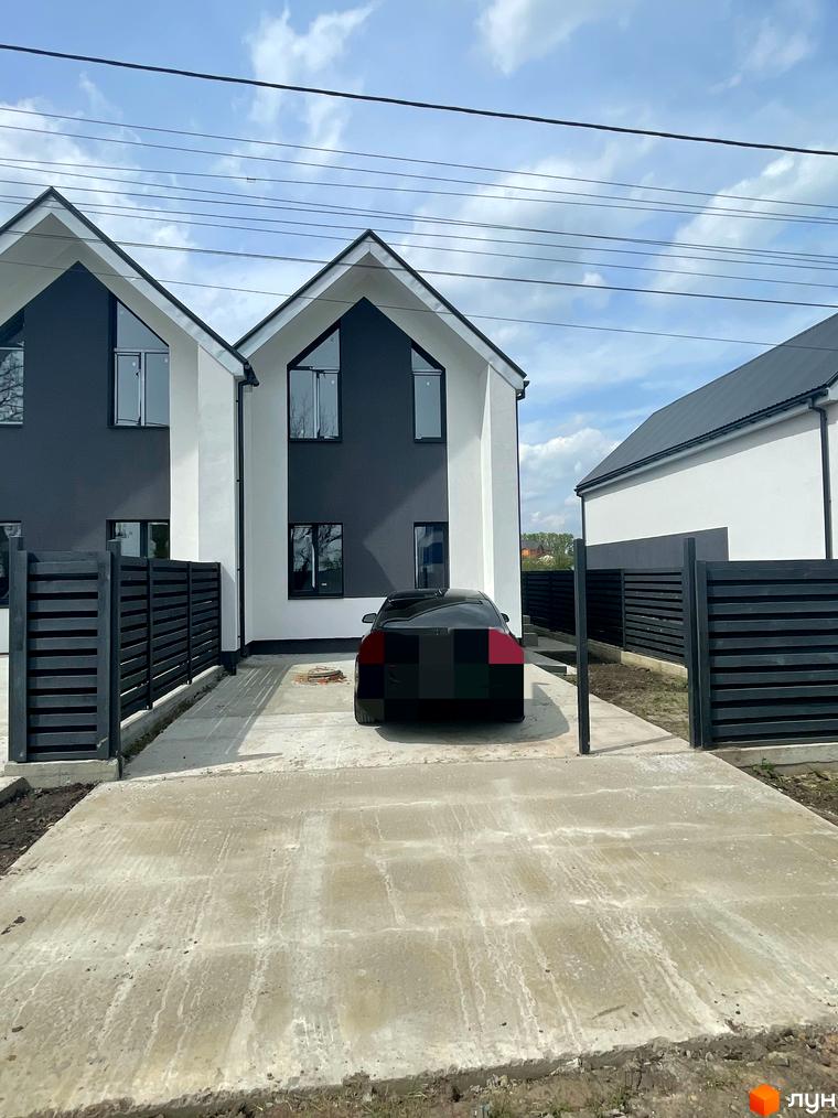 Зовнішній вигляд дуплексів „На Зоряному“ з чорними та білими фасадами, сучасними вікнами та чорною огорожею. Прибудинкова територія з бетонною доріжкою та автомобілем.