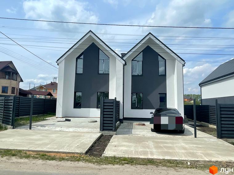 Зовнішній вигляд дуплексів „На Зоряному“ з білими та темними фасадами, розташованих на заасфальтованій ділянці з парканом.