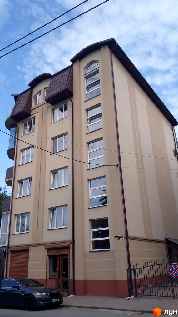 Житловий комплекс на вул. Родини Барвінських, 16. Бежевий будинок з коричневим мансардним дахом, арковими вікнами та прибудинковою територією.