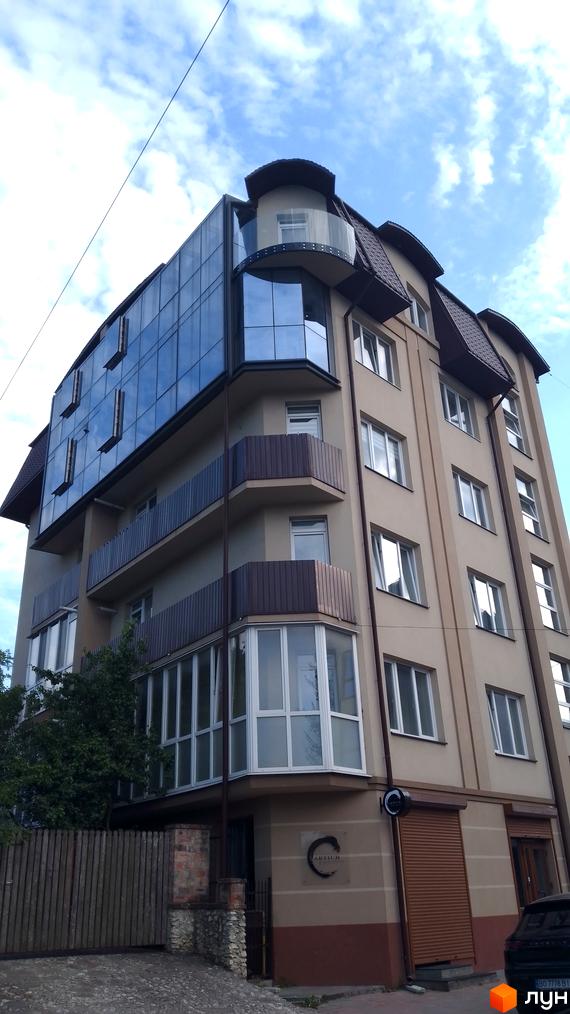 Житловий комплекс ARTIUM на вул. Родини Барвінських, 16 з багатоповерховим фасадом зі скла та бежевих стін, балконами та коричневим дахом.