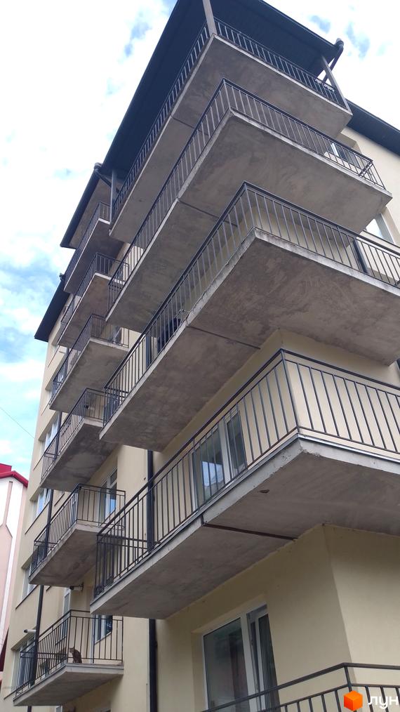 Фасад багатоповерхової новобудови світлого кольору з бетонними балконами та темними перилами. Житловий комплекс на вул. Крушельницької, 35а.