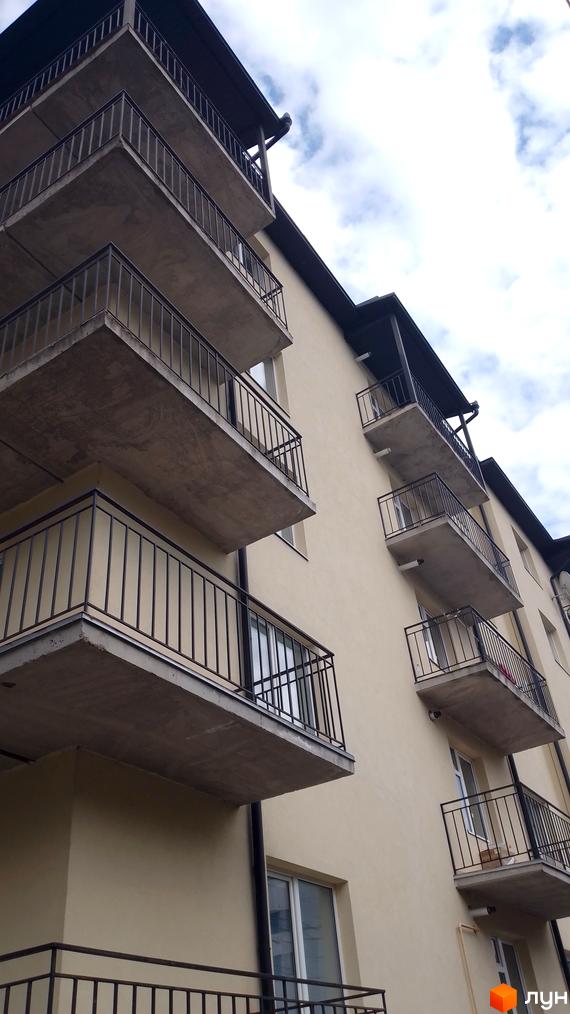 Фасад багатоквартирного будинку світлого кольору з балконами та металевими огорожами. Новобудова на вул. Крушельницької, 35а.