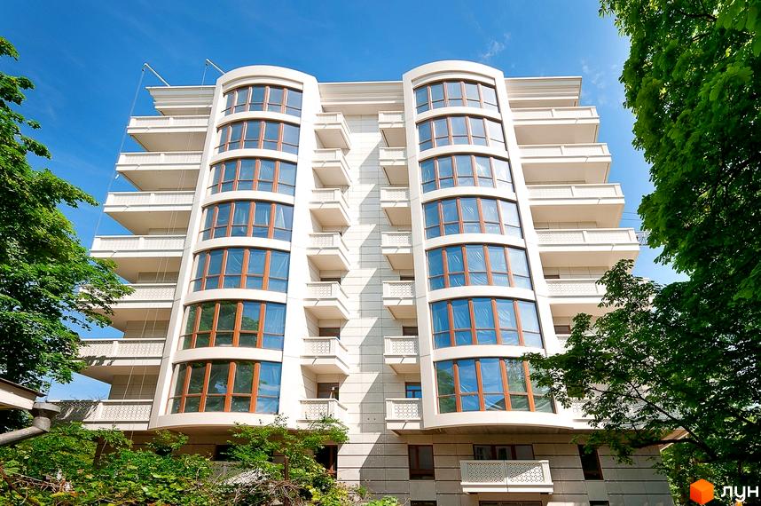 Зображення фасаду Житлового комплексу Біла акація з великими вікнами та балконами. Вигляд новобудови на фоні блакитного неба та зелених дерев.