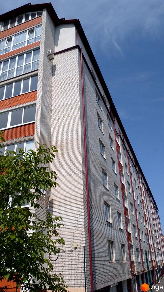 Багатоповерховий житловий будинок на вул. Рєпіна, 34, з фасадом з білої цегли, червоними акцентами та зеленими насадженнями.