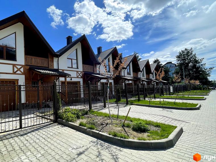 Таунхауси Desna Residence-2 з білими фасадами, дерев'яними елементами та темними дахами. Прибудинкова територія має бруківку та зелені насадження.