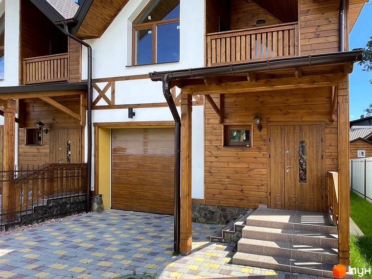 Таунхаус Desna Residence-2 з дерев'яним фасадом, коричневим дахом, ганком та гаражем. Подвір'я вимощене плиткою.