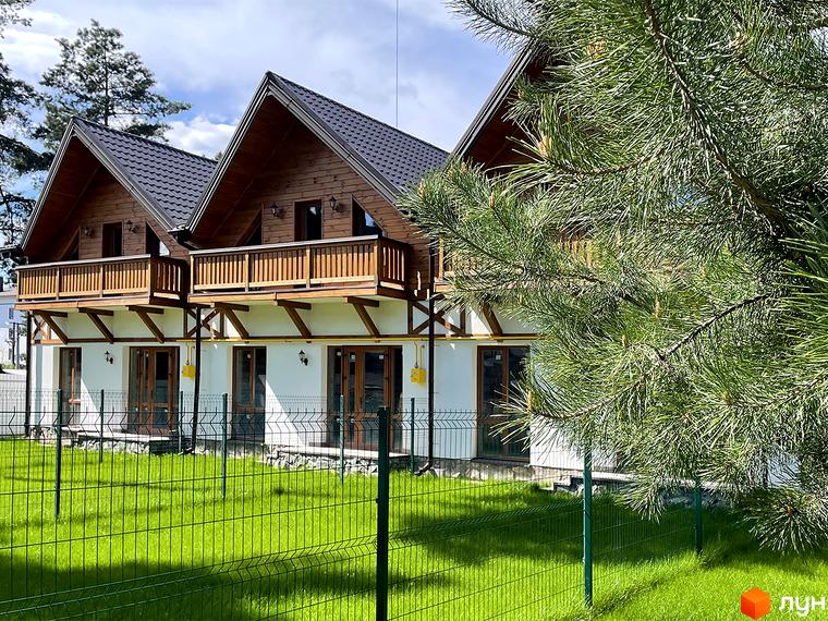 Таунхауси Desna Residence-2 з дерев'яними фасадами, темними дахами та балконами. Перед будинками зелений газон і сітчастий паркан.