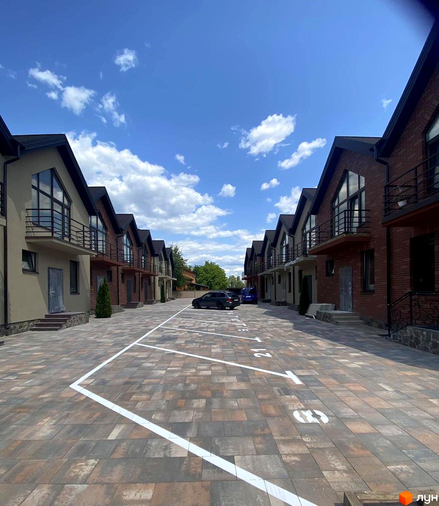 Ряд двоповерхових будинків з панорамними вікнами та балконами. На території комплексу Modern House є паркувальні місця.