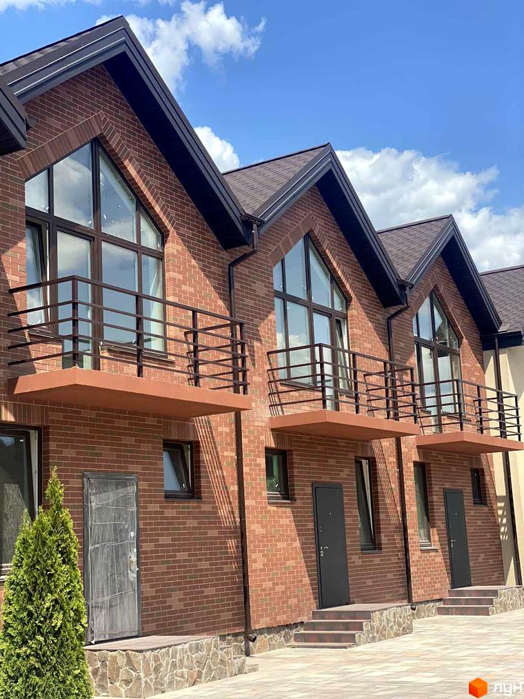 Фасад таунхаусів Modern House з цегляною кладкою, балконами та великими вікнами. На території комплексу висаджені дерева та кущі.
